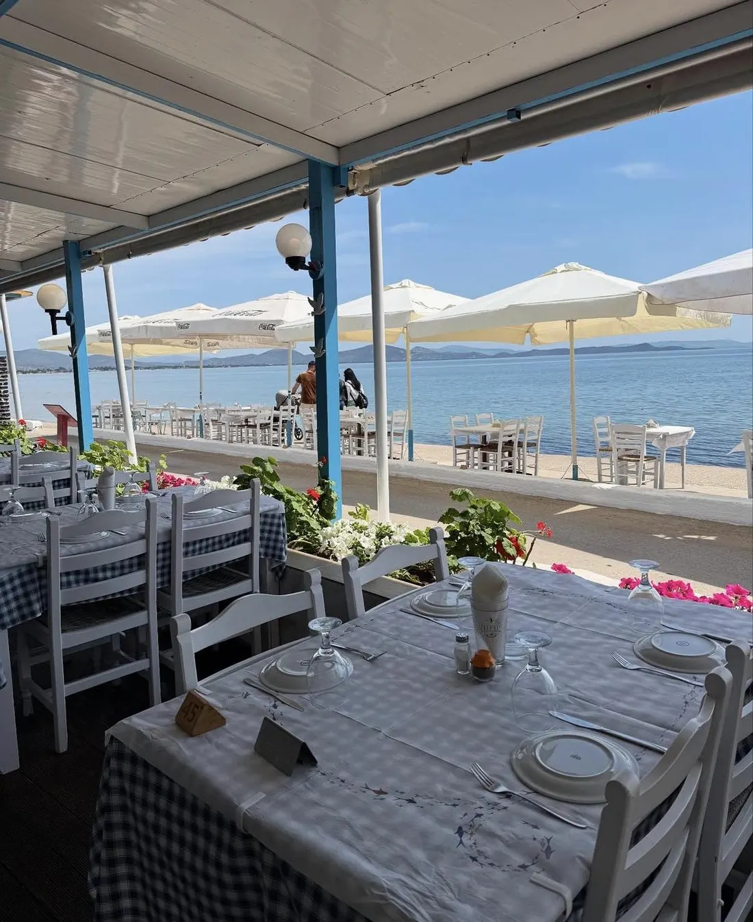Στρωμένο τραπέζι στη βεράντα της Αργώς, με ομπρέλες στον πεζόδρομο και θέα στη θάλασσα